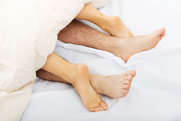 Fototapeta na wymiar Couple's feet in bed.