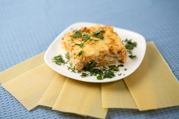 Lasagna with greens on a plate on a blue napkin, macaroni with chicken forcemeat