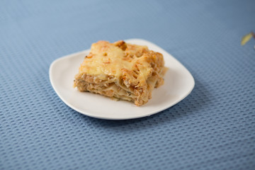 Lasagna with greens on a plate on a blue napkin, macaroni with chicken forcemeat