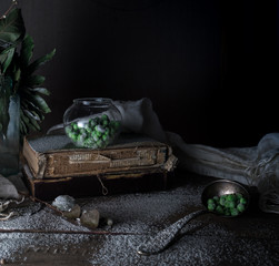 rustic still life, vintage. green peas, old books, flour on a wooden table. dark background