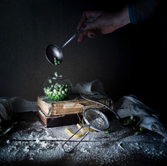 female hand pours into a glass jar peas. vintage. dark background