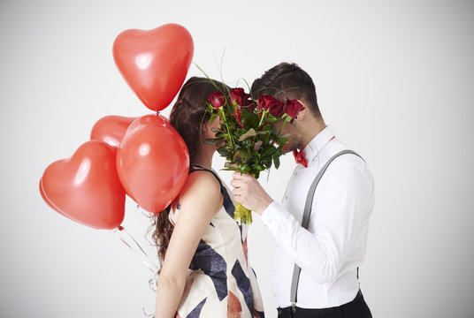 Bouquet of red roses covering couple kiss