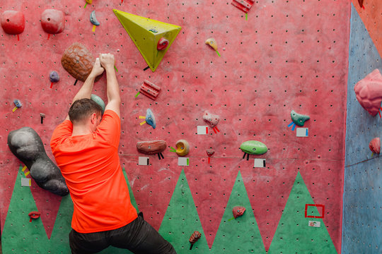 Sport man exercising on artificial climbing wall, modern leisure concept
