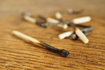 Heap of burnt matches on the wooden background as a symbol of exhaustion, depletion and destruction 