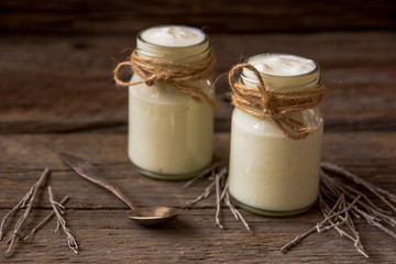 Yogurt in jars on the wooden table with dried plant