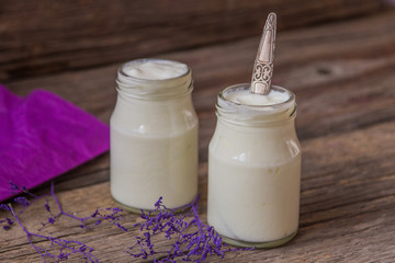 Yogurt in jar on the wooden table with purple dried plant