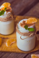 Fresh organig natural white yogurt in glass jars with tangerine