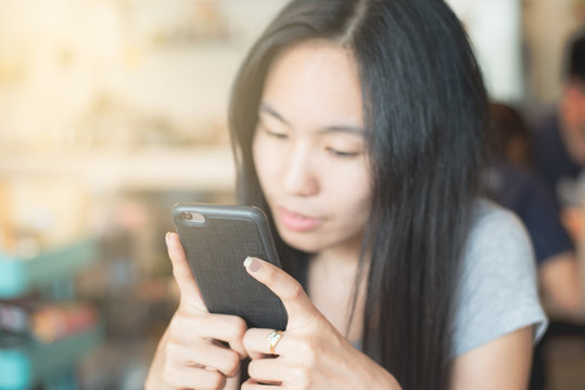 Young lady chatting, using smartphone, hold cell phone  and looking at  the  cell phone