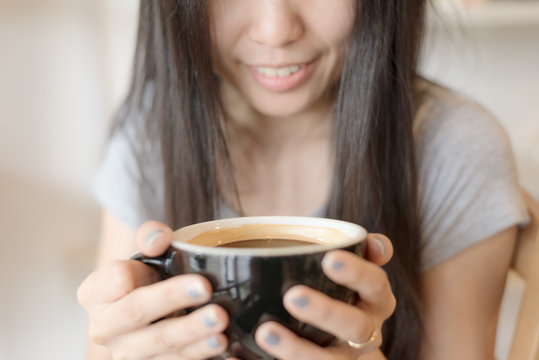 Young lady smiling and hold hot black coffee cup by two hands