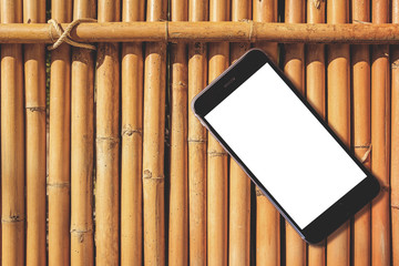 Blank smart phone on bamboo wooden table background with copy space
