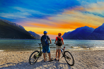 Mountain biking, couple with bikes at sunset on Lake Garda, Riva