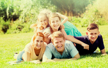Happy man and woman with four kids lying in park