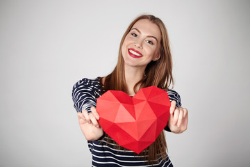 Smiling woman holding red polygonal paper heart shape