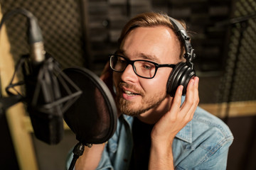 man with headphones singing at recording studio