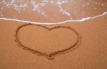 Heart drawn in the sand and waves background. Valentines day. Sy