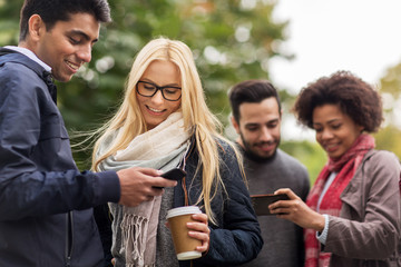 Obraz premium happy friends with smartphone and coffee outdoors
