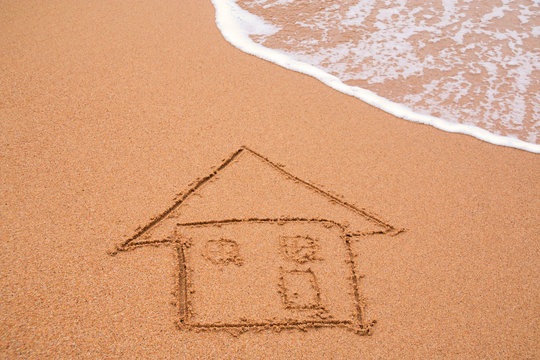 painted home on sand of beach with wave on background