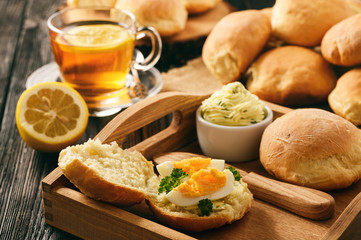 Home breakfast - homemade bread rolls, cup of tea, boiled eggs and garlic herb butter.