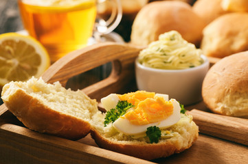 Home breakfast - homemade bread rolls, cup of tea, boiled eggs and garlic herb butter.