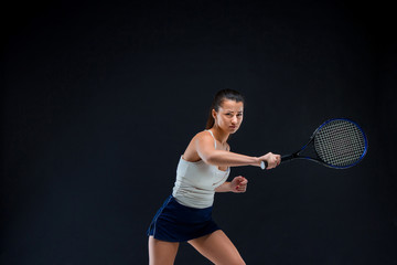 Portrait of beautiful girl tennis player with a racket on dark background