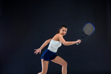 Portrait of beautiful girl tennis player with a racket on dark background