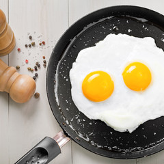 Fried eggs for delicious healthy easy breakfast on a table. Fresh homemade meal on a frying pan. Traditional breakfast food. International cuisine food.  Top view.