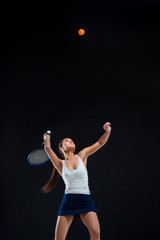 Portrait of beautiful girl tennis player with a racket on dark background