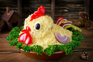 Salad shaped rooster on a plate on a wooden table