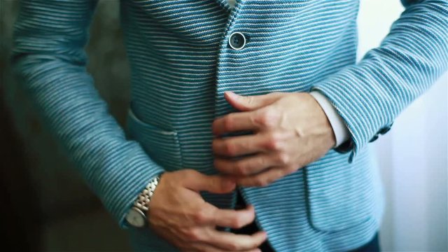 Man hands buttoning casual outfit jacket close up. Stylish well-dressed man trying on blue striped suit preparing to go out. Macho luxury fit size garment golden youth style establishment concept