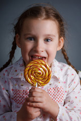 child girl eating and licking with tongue big multicolor spiral lollipop candy