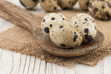 Quail eggs in a wooden spoon and an old wooden table.