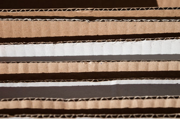 Obraz premium Texture of layered brown cardboard side. Folded cardboard boxes. Wavy paper texture on sunlight with copy space.