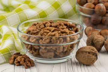 Walnuts in a glass bowl on an old white wooden table.