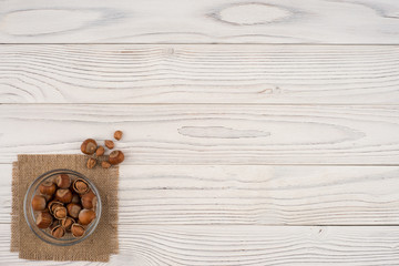 Hazelnut in a glass bowl on an old white wooden table.