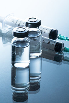 medical ampoules and syringe on blue background.