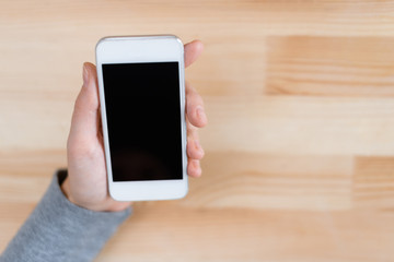 Hand holds a phone on wooden background