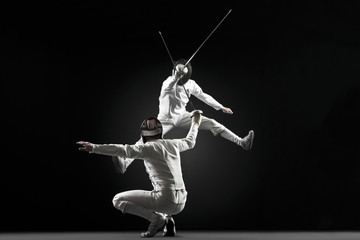 Fencers fencing, one fencer jumping in air