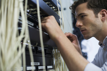 Computer technician performing maintenance on computer networking equipment