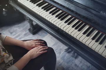 Girl near an old piano. Close-up of hands