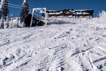 Lysa hora hill in winter Moravskoslezske Beskydy mountains with ski lift, mountain chalet, snow and clear sky