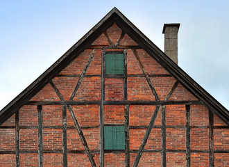 Facade of an old half-timbered buildings of red brick with pitched roof and with wooden frame.