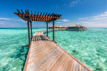 Wooden jetty towards water villas in Maldives. - obrazy, fototapety, plakaty
