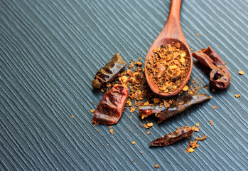 Red chili dry pepper and wood spoon on black wood background