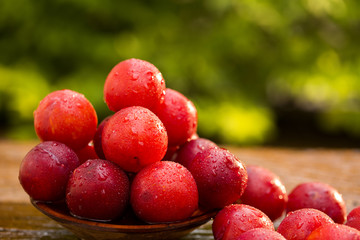 Fresh bright plums on wooden background