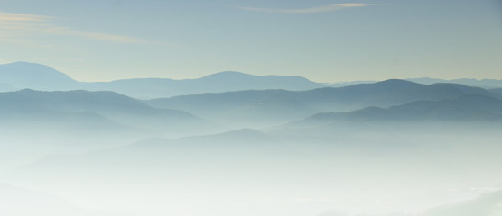 Mountain layer in morning sun ray and winter fog.