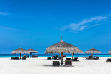 Sandy tropical beach with deckchairs and sunshades. Maldives