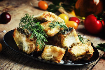 Fried fish, pieces of mullet with dill on a plate. Vintage woode