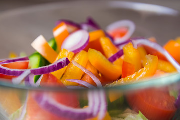 Fresh Salad in a Glass Bowl with Onions, Bell Pepper and Tomatos