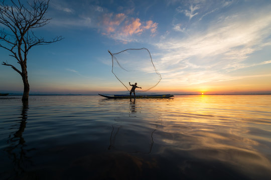 Silhouette of traditional fishermen throwing net fishing lake at sunset time,Asia,Thailand