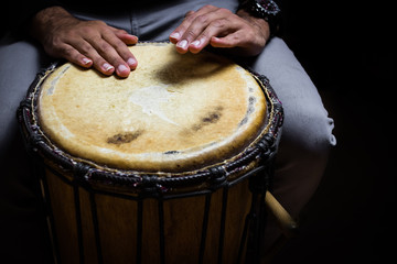 Musician playing Sinlge West African Drum in Dramatic Single Light.
